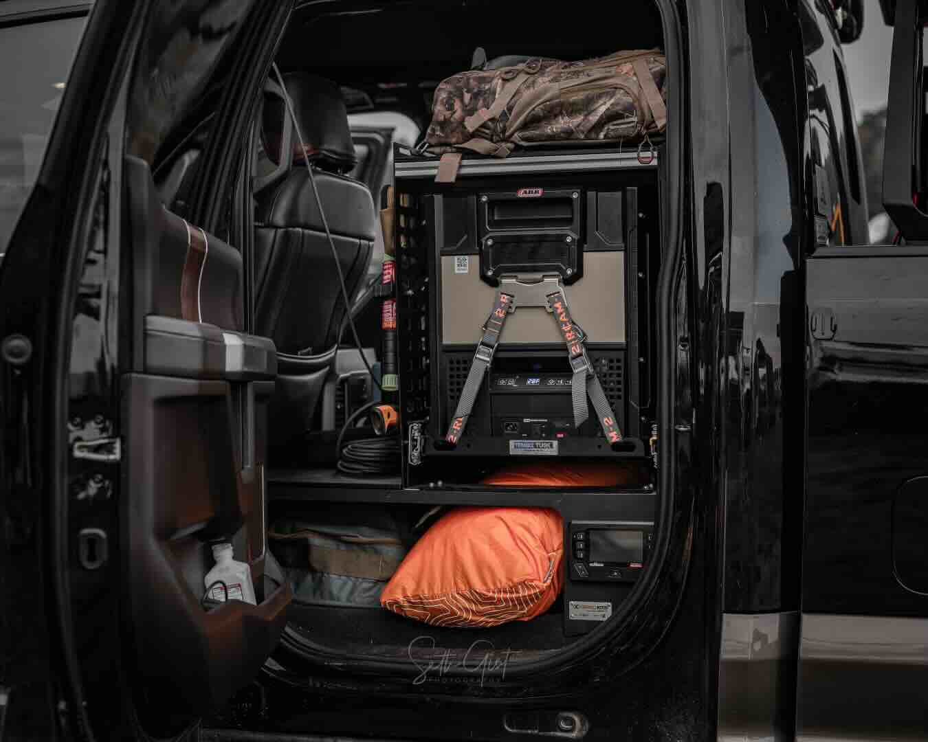 A custom rear seat delete kit in a Ford F-250, featuring a refrigerator slide out, dual battery system, storage compartments.